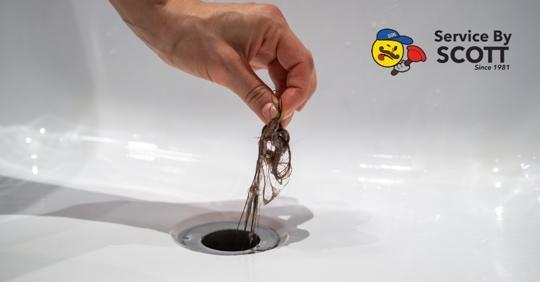 person pulling hair out of a drain